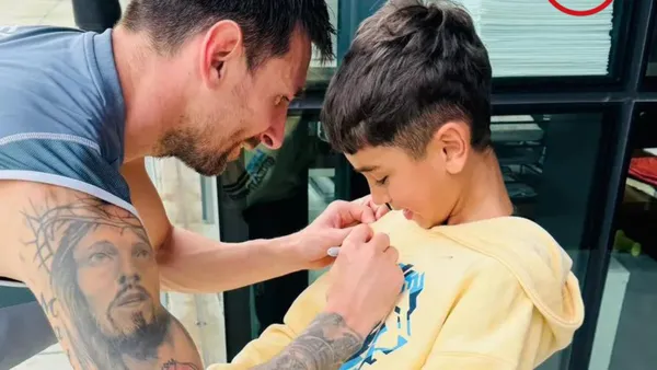 Messi firmando el buzo del hijo de Troglio