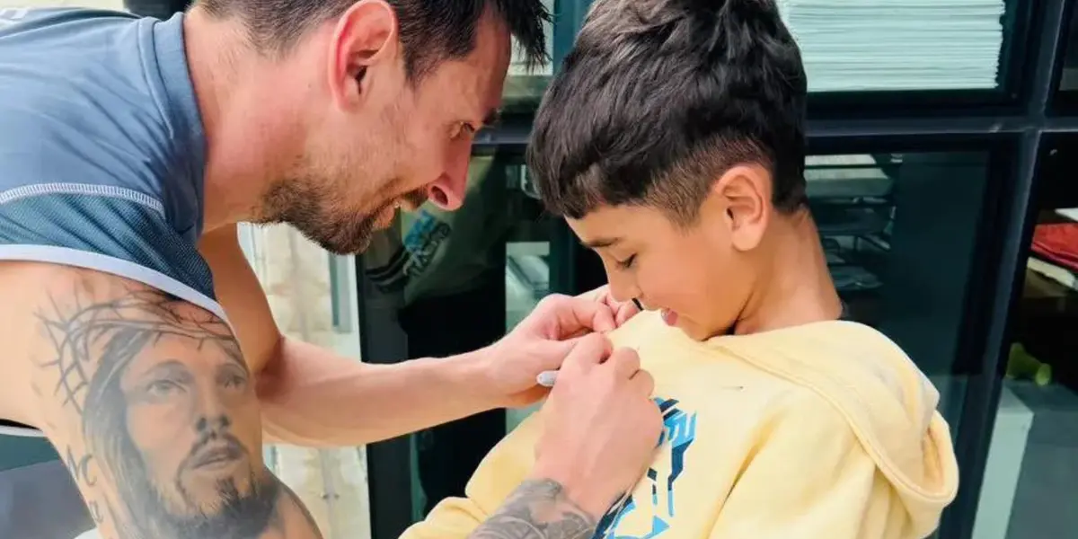 Messi firmando el buzo del hijo de Troglio