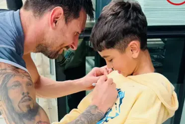 Messi firmando el buzo del hijo de Troglio
